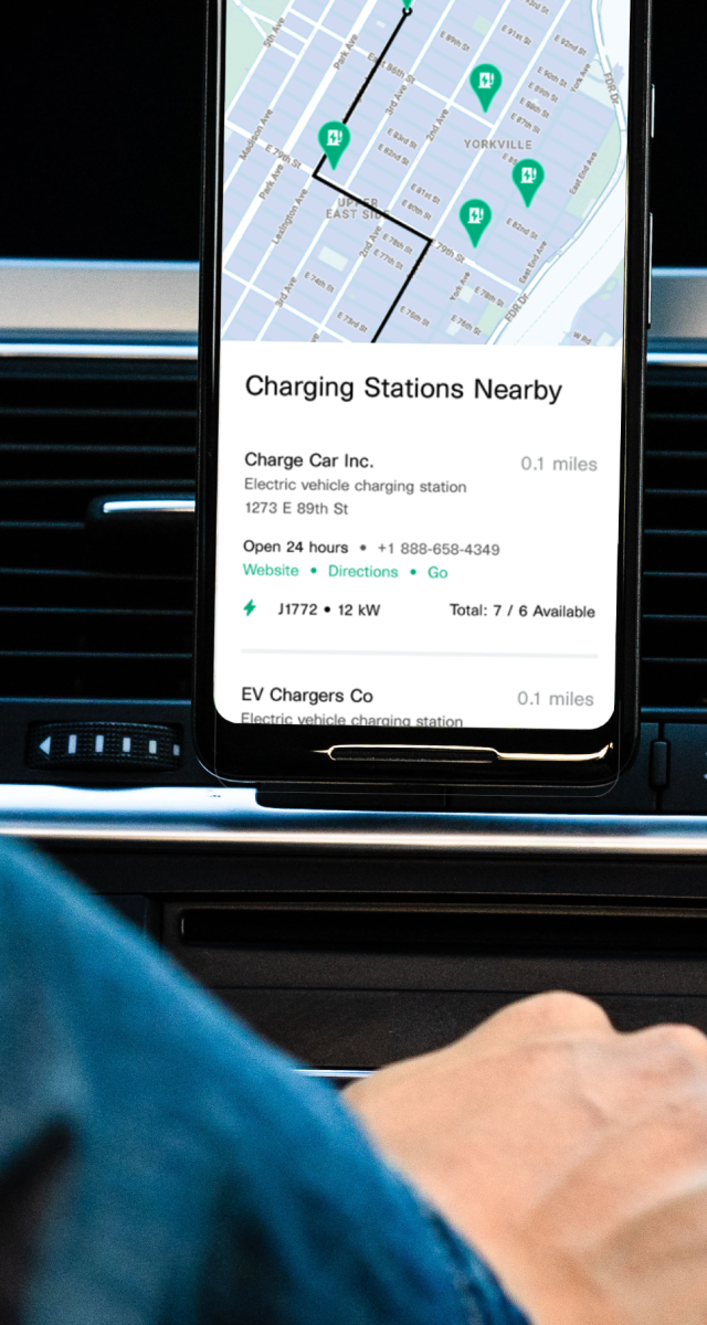 Driver getting information from a mobile phone about nearby charging stations.
