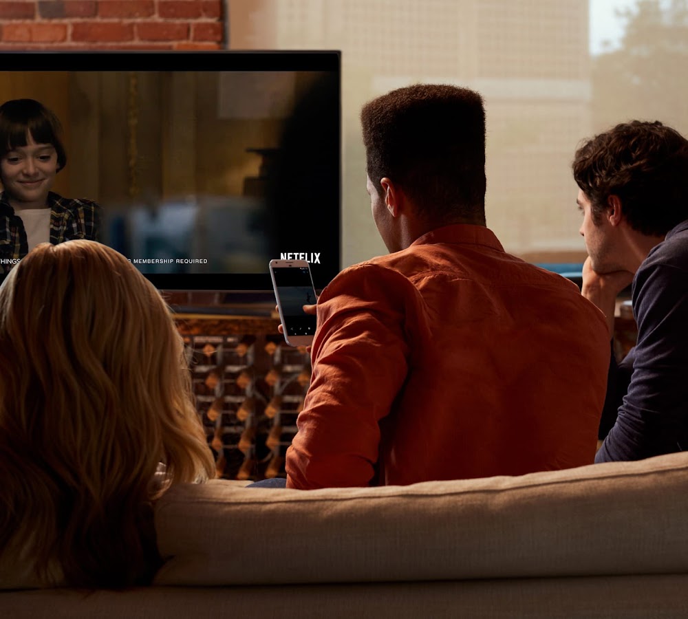 Three people in a coach watching TV