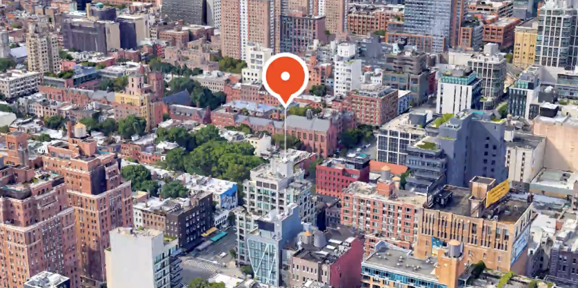An overhead view of a city building with a map marker above it.