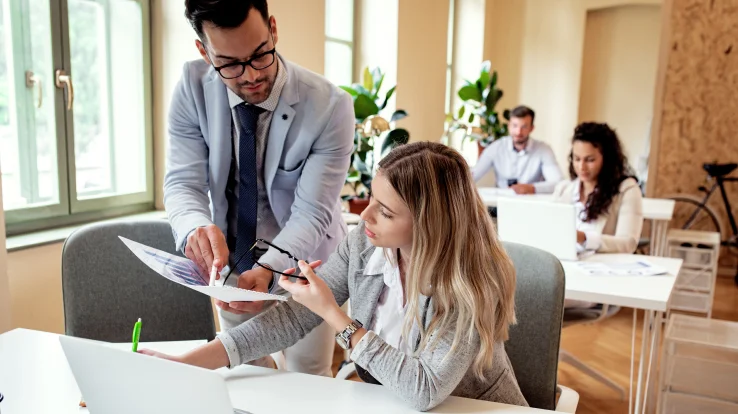 Woman and man at a desk looking over a chart. 