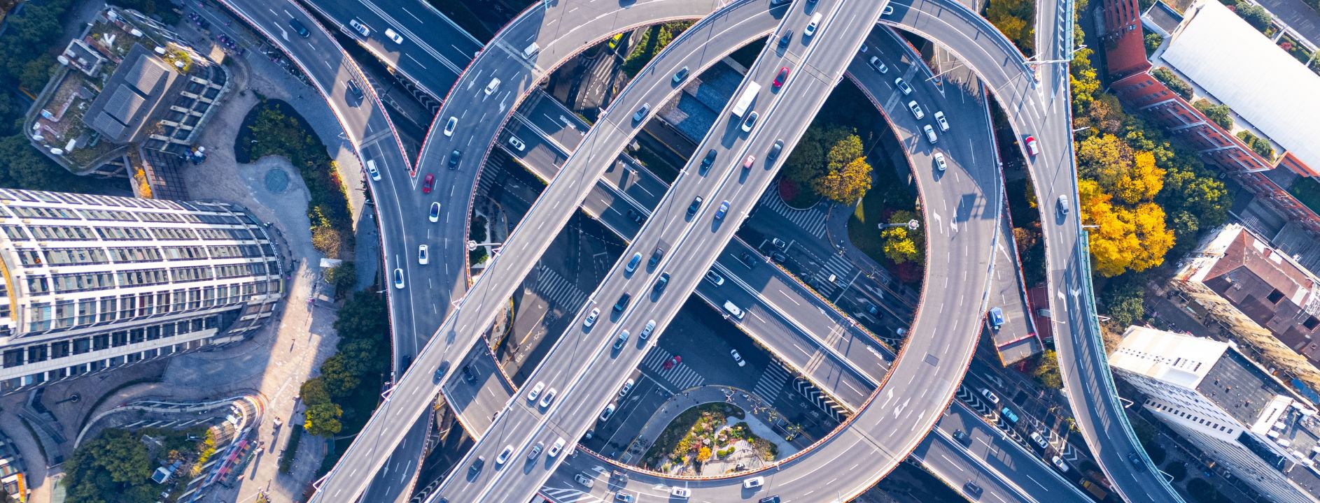 Vista aérea de un complejo intercambiador de carreteras de varios niveles en una ciudad, con el tráfico fluyendo a través de pasos elevados circulares.