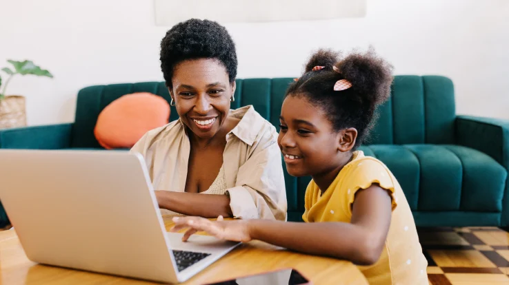 Woman with her daughter working on her laptop. 