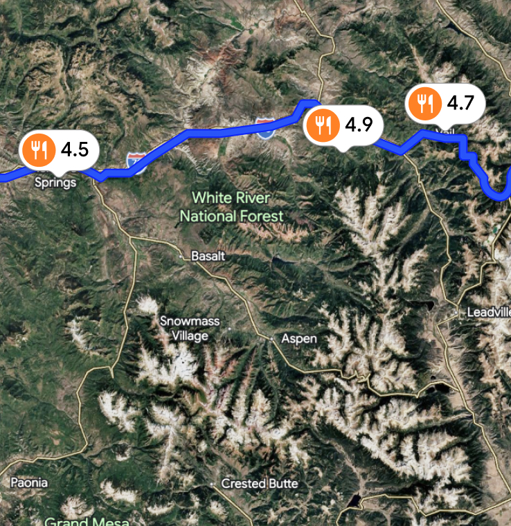 Satellite map of White River National Forest region with a blue driving route and restaurant rating pins along I-70.