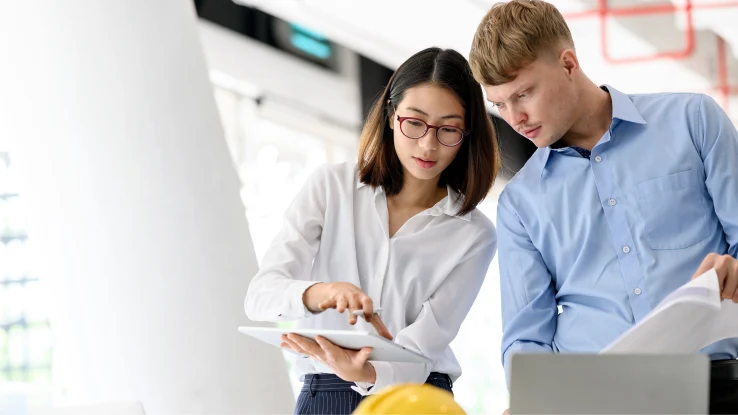 Woman and man in an office looking at a tablet. 