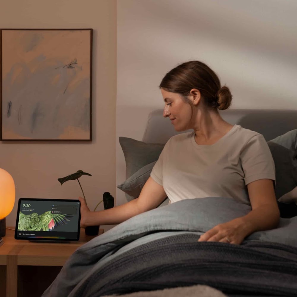 A woman using Google Assistant on the her tablet to turn on the lights